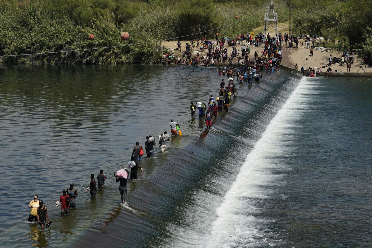 FILE - In this Sept. 18, 2021, file photo Haitian migrants use a dam to cross into the United States from Mexico in Del Rio, Texas. President Joe Biden embraced major progressive policy goals on immigration after he won the Democratic nomination, and he has begun enacting some. But his administration has been forced to confront unusually high numbers of migrants trying to enter the country along the U.S.-Mexico border and the federal response has inflamed both critics and allies. (AP Photo/Eric Gay, File)