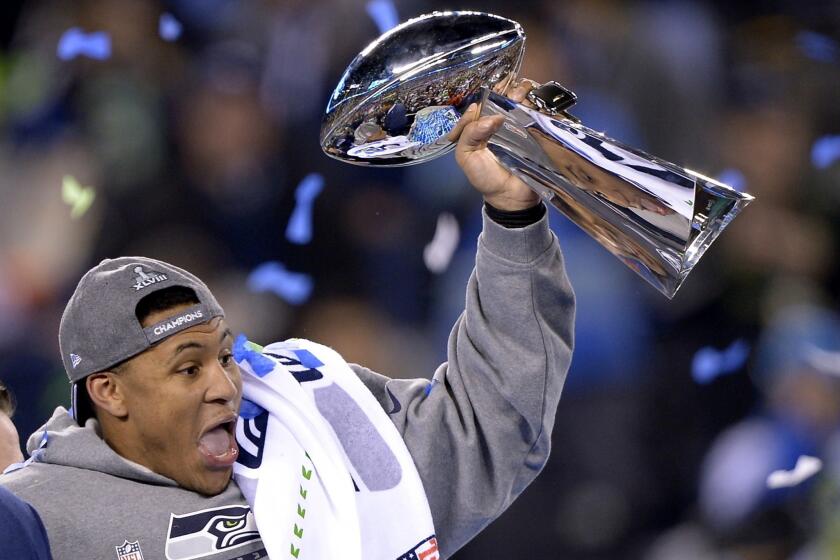 Seattle linebacker Malcolm Smith, who returned an interception for a touchdown and recovered a fumble, holds aloft the Most Valuable Player trophy after the Seahawks defeated the Denver Broncos, 43-8, in Super Bowl XLVIII.