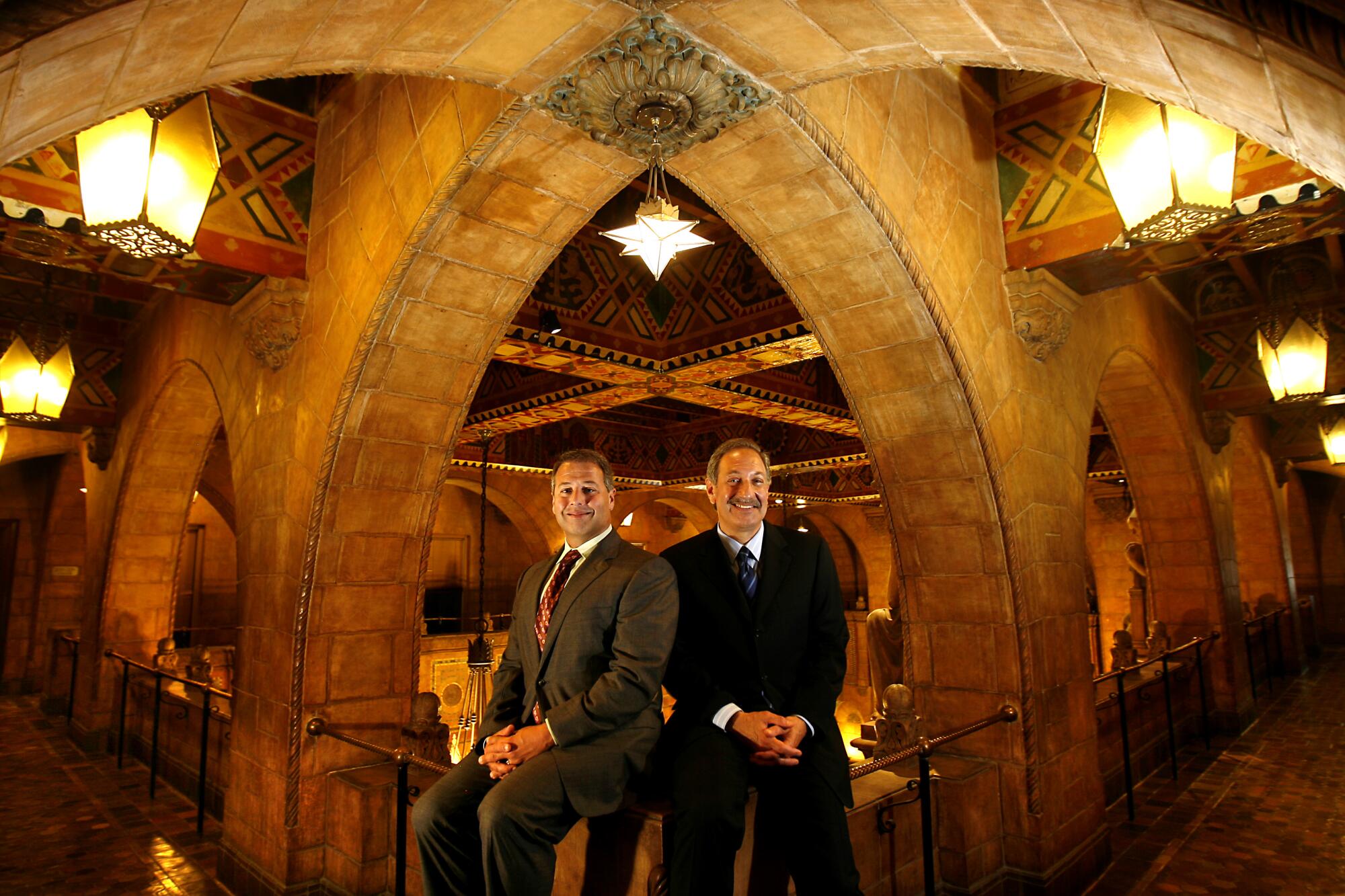 Two men sitting inside an ornate building.