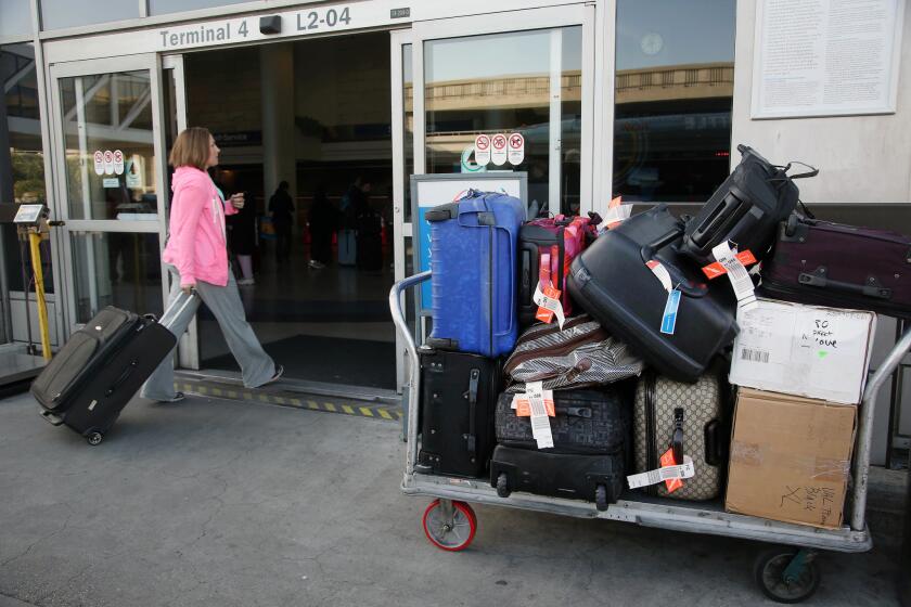 A traveler passes a stacked cart of luggage while entering LAX's Terminal 4.