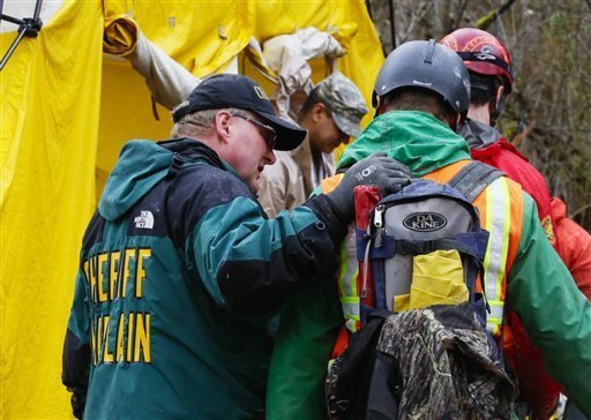 A sheriff's chaplain offers a few words to a rescue worker in Arlington, Wash., on Sunday.