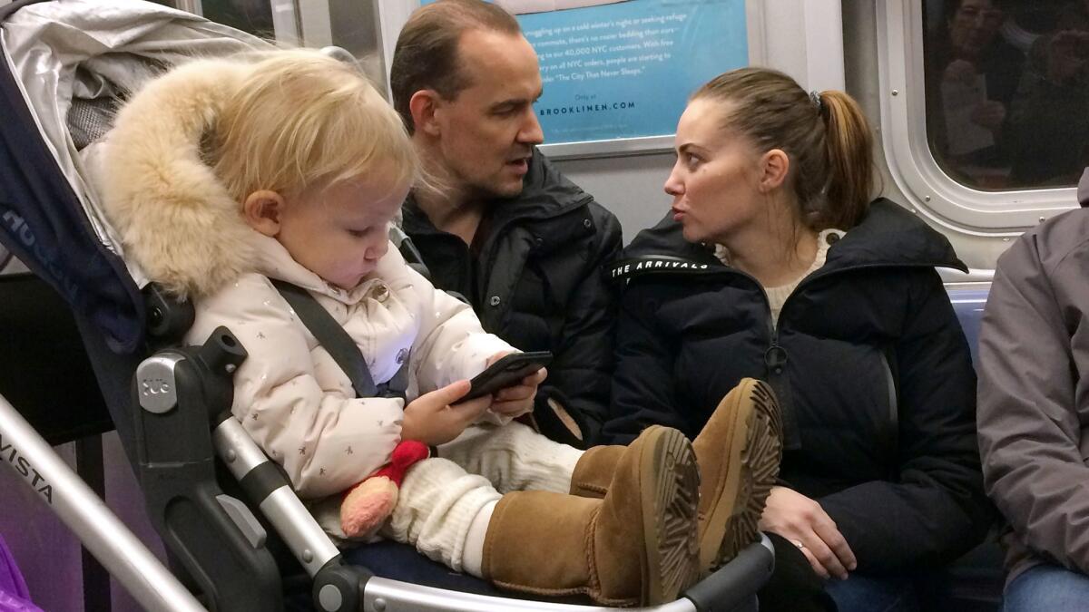 A child plays with a smartphone while riding a subway train in New York.