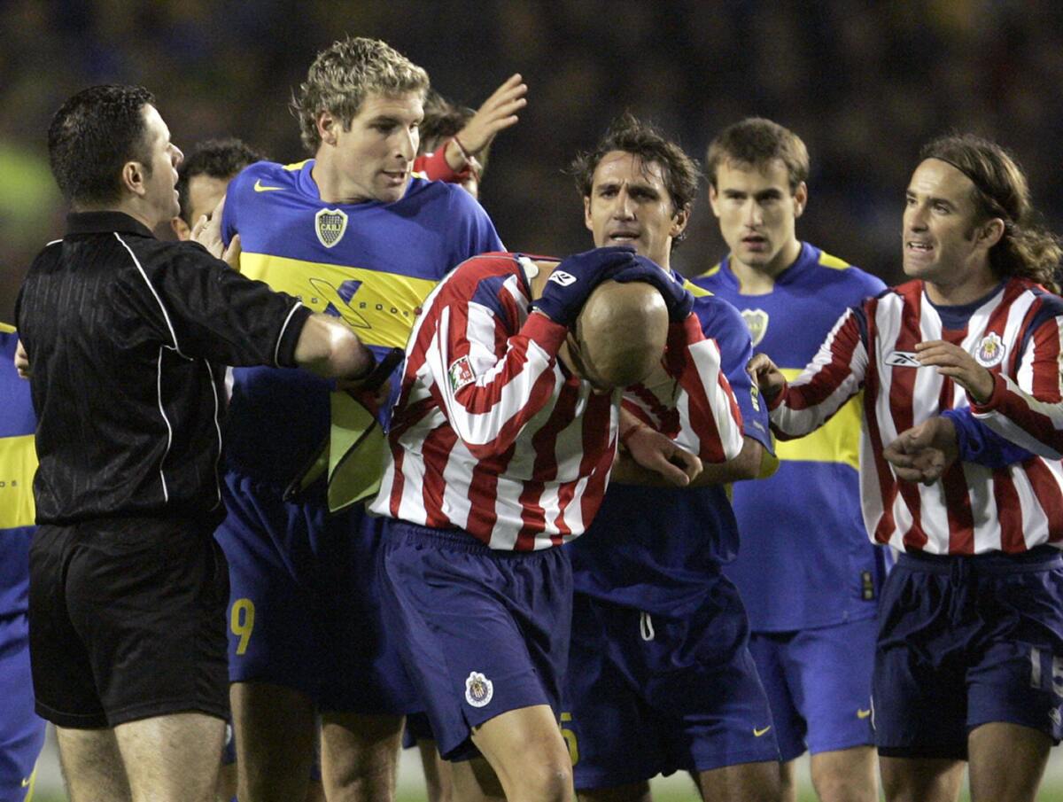 BUENOS AIRES, ARGENTINA: Chivas of Guadalajara's Adolfo Batista (C) covers his head, as referee Martina Vazquez (L) and teammate Manuel Sol (R) try to stop Boca Juniors' Martin Palermo (2nd-L), Raul Cascini (C, behind) and Rodrigo Palacio 14 June, 2005 shortly before the end of their Libertadores Cup quarterfinals match at La Bombonera stadium in Buenos Aires. Both teams tied 0-0 and Chivas qualified for the semifinals. AFP PHOTO Daniel GARCIA (Photo credit should read DANIEL GARCIA/AFP via Getty Images)