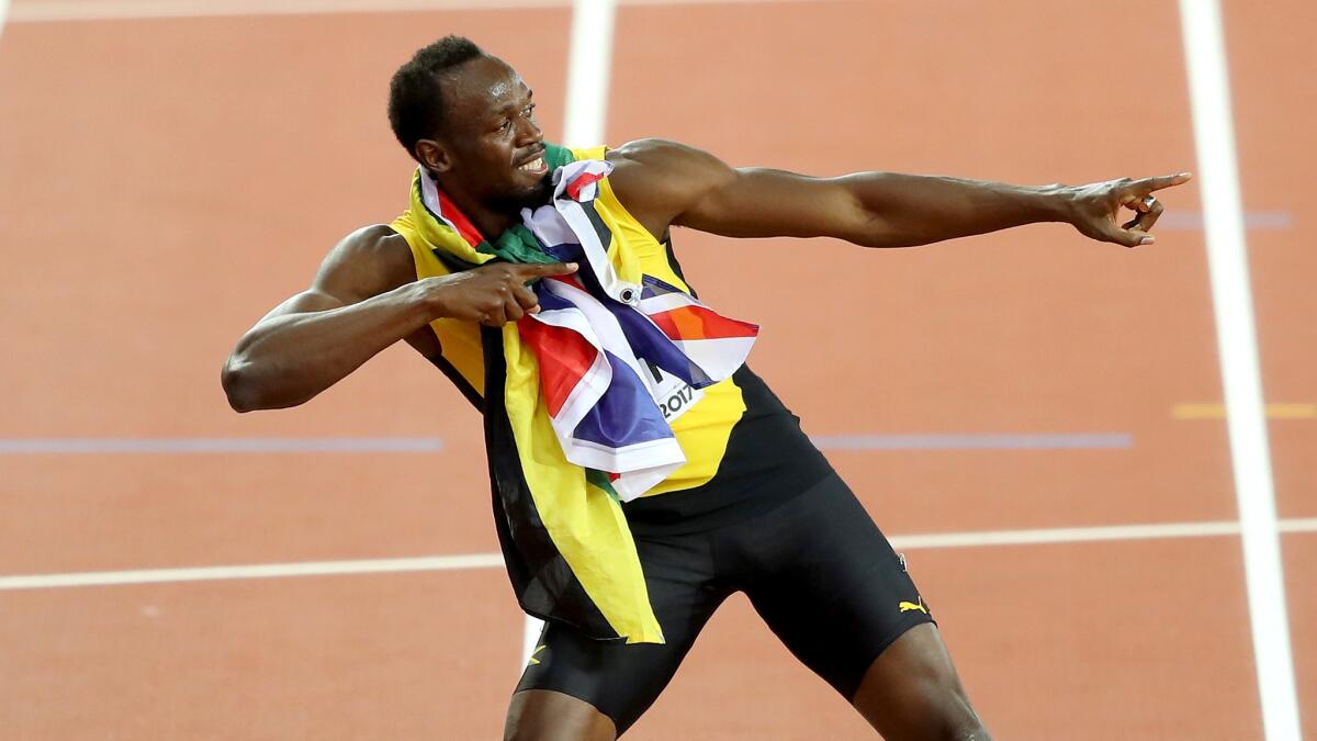 Usain Bolt strikes his familiar pose during a lap around London's Olympic Stadium following his third-place finish in the 100 meters at the world championships Saturday.