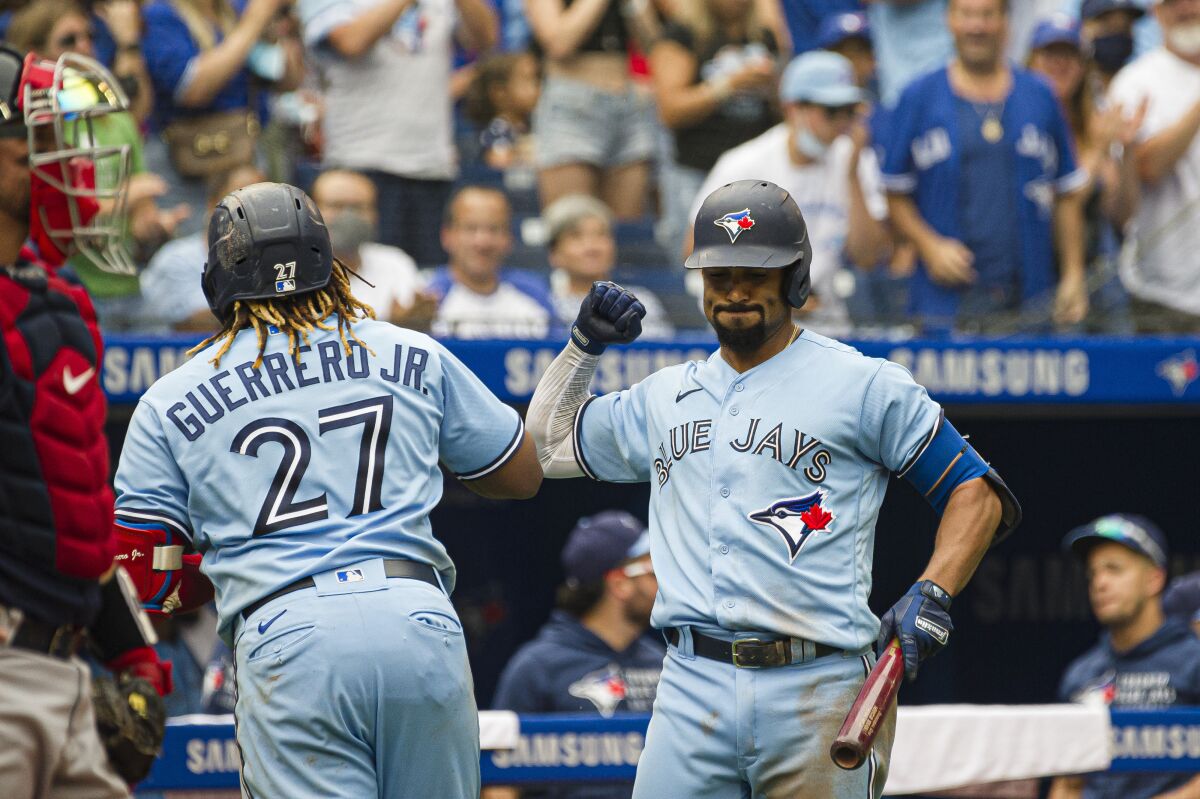 Toronto Blue Jays' Vladimir Guerrero Jr. (27) and Marcus Semien (10) celebrate after Guerrero Jr. hits a home run during the fifth inning of a baseball game against the Boston Red Sox, Sunday, Aug. 8, 2021 in Toronto. (Christopher Katsarov/The Canadian Press via AP)