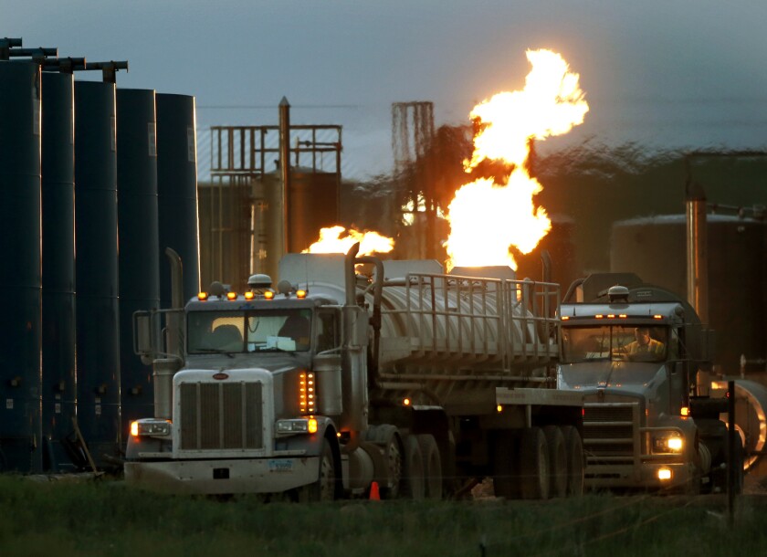 Tanker trucks for hauling water and fracking fluids line up near a natural gas flare in Williston, N.D. Fracking has touched off a nationwide oil and gas boom, and with it, worries about public health and the environment.