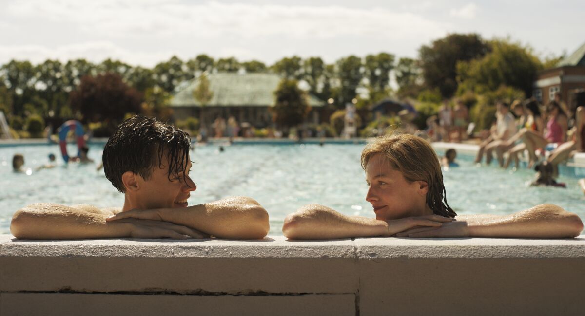 Harry Styles and Emma Corrin's characters rest at the edge of a pool in "My Policeman."