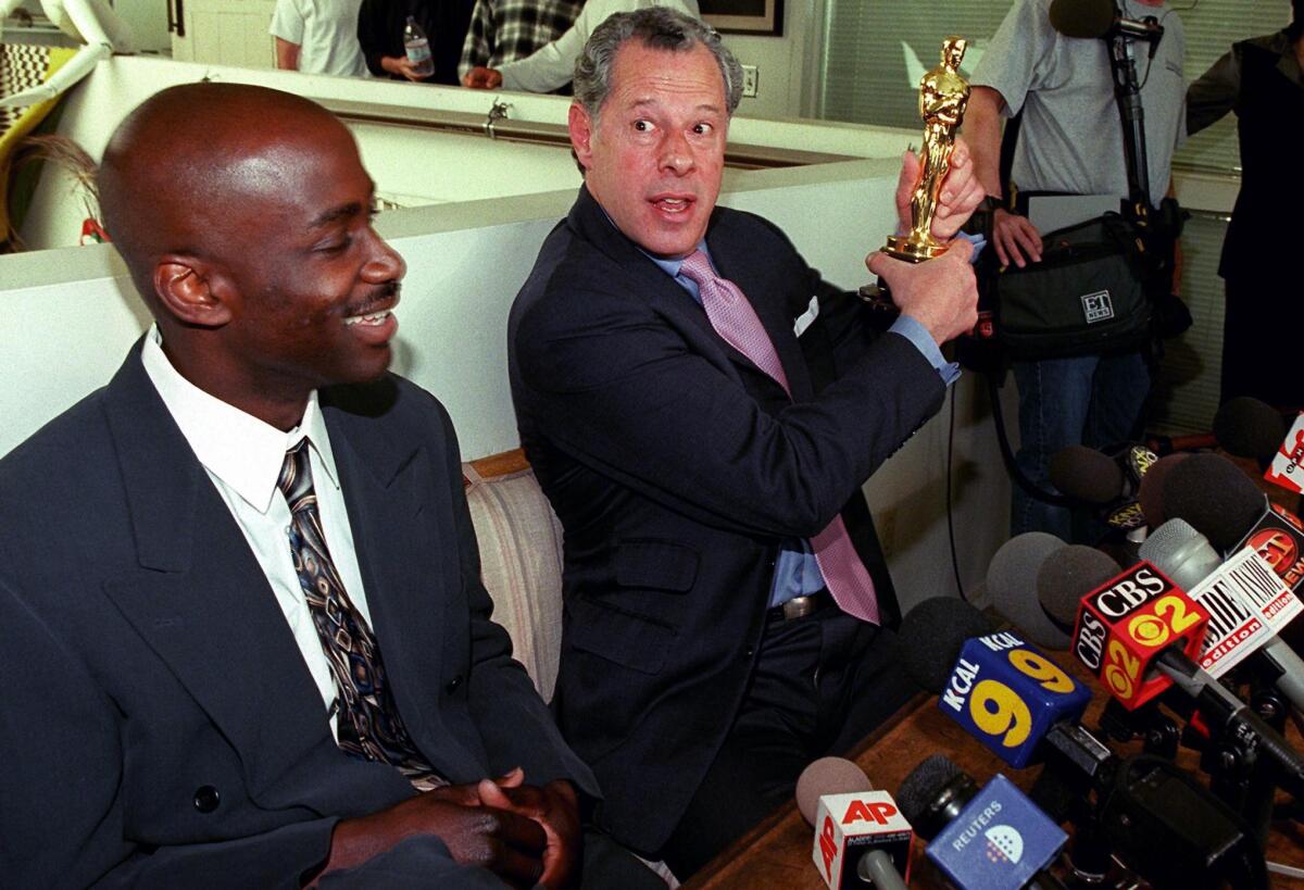 Lawyer Stephen Yagman holds an Oscar statue in front of news microphones