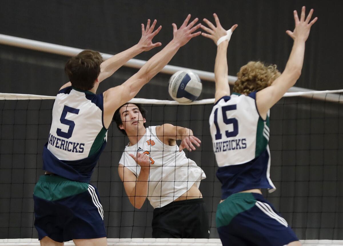 Huntington Beach's Trent Douphner kills the ball between two Carlsbad La Costa Canyon defenders.  