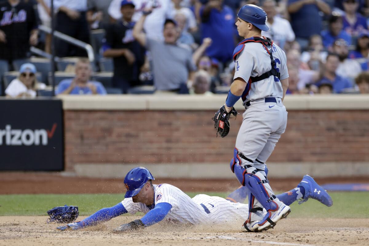 New York's Brandon Nimmo slides across the plate to score in front of Dodgers catcher Will Smith.