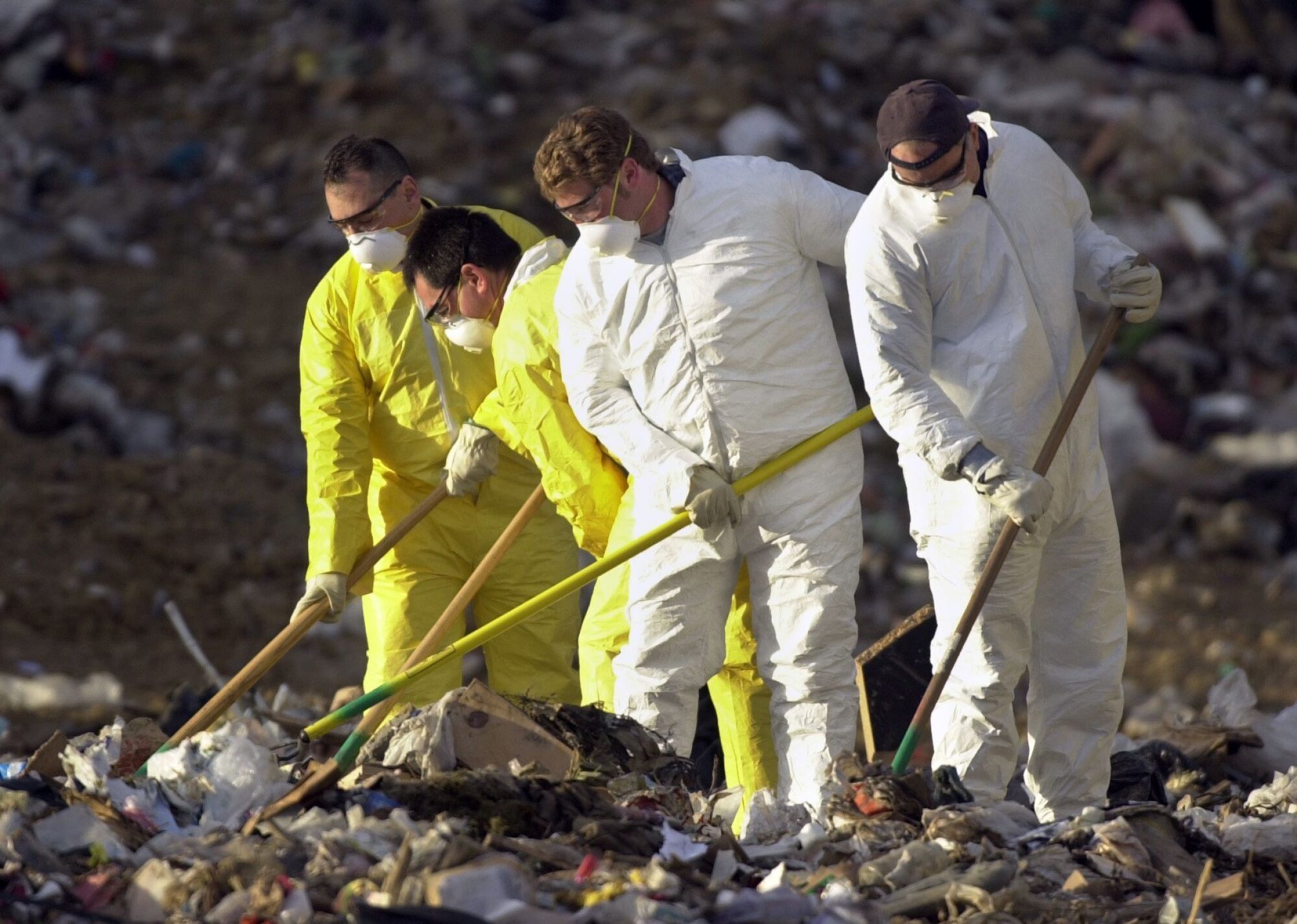 San Diego police officers sift through trash at the Miramar Landfill on Tuesday, April 30, 2002.