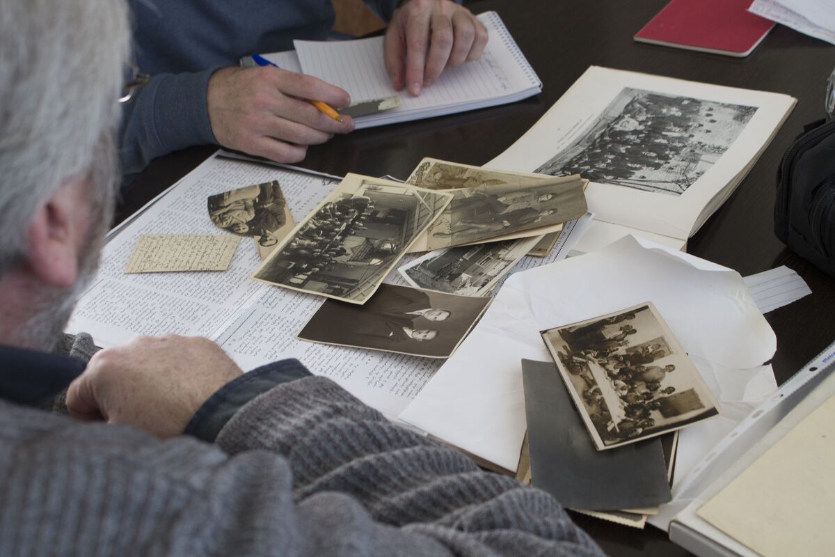Vahé Tachjian takes notes and examines family photos