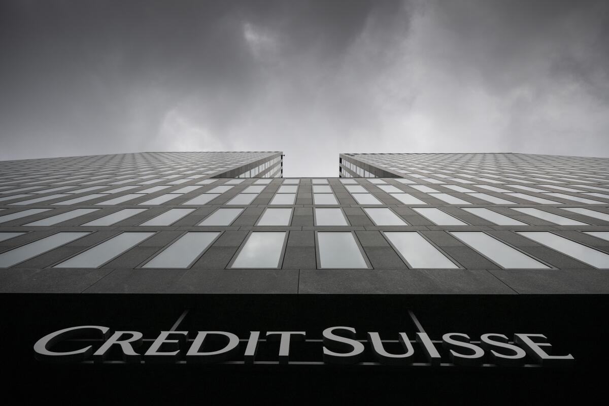 Gray clouds cover the sky over a Credit Suisse bank building