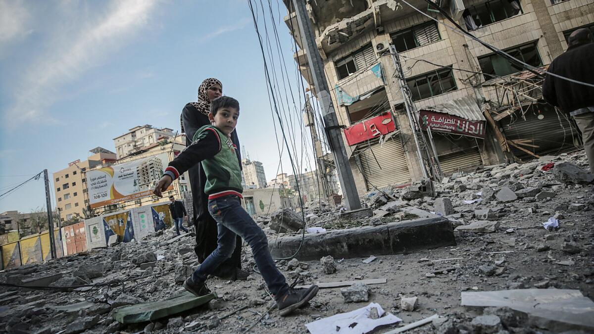 A Palestinian boy and his mother walk through the rubble of a destroyed building on Sunday after an Israeli airstrike in Gaza City.