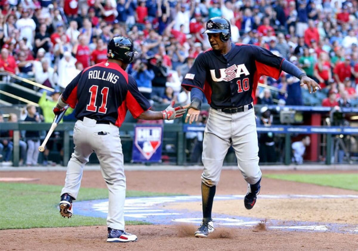 Adam Jones (10) of USA celebrates with Jimmy Rollins (11) after scoring a run against Canada.