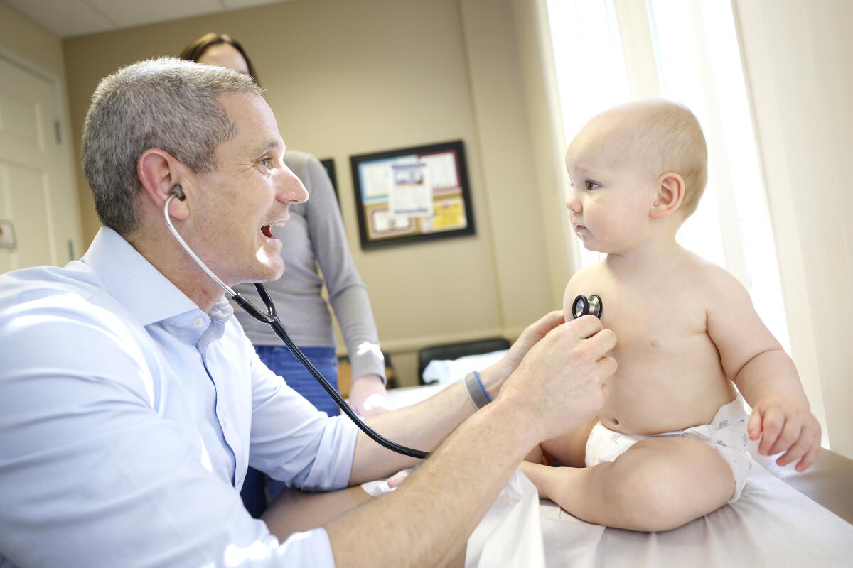 A doctor holding a stethoscope to the chest of a 9-month-old baby