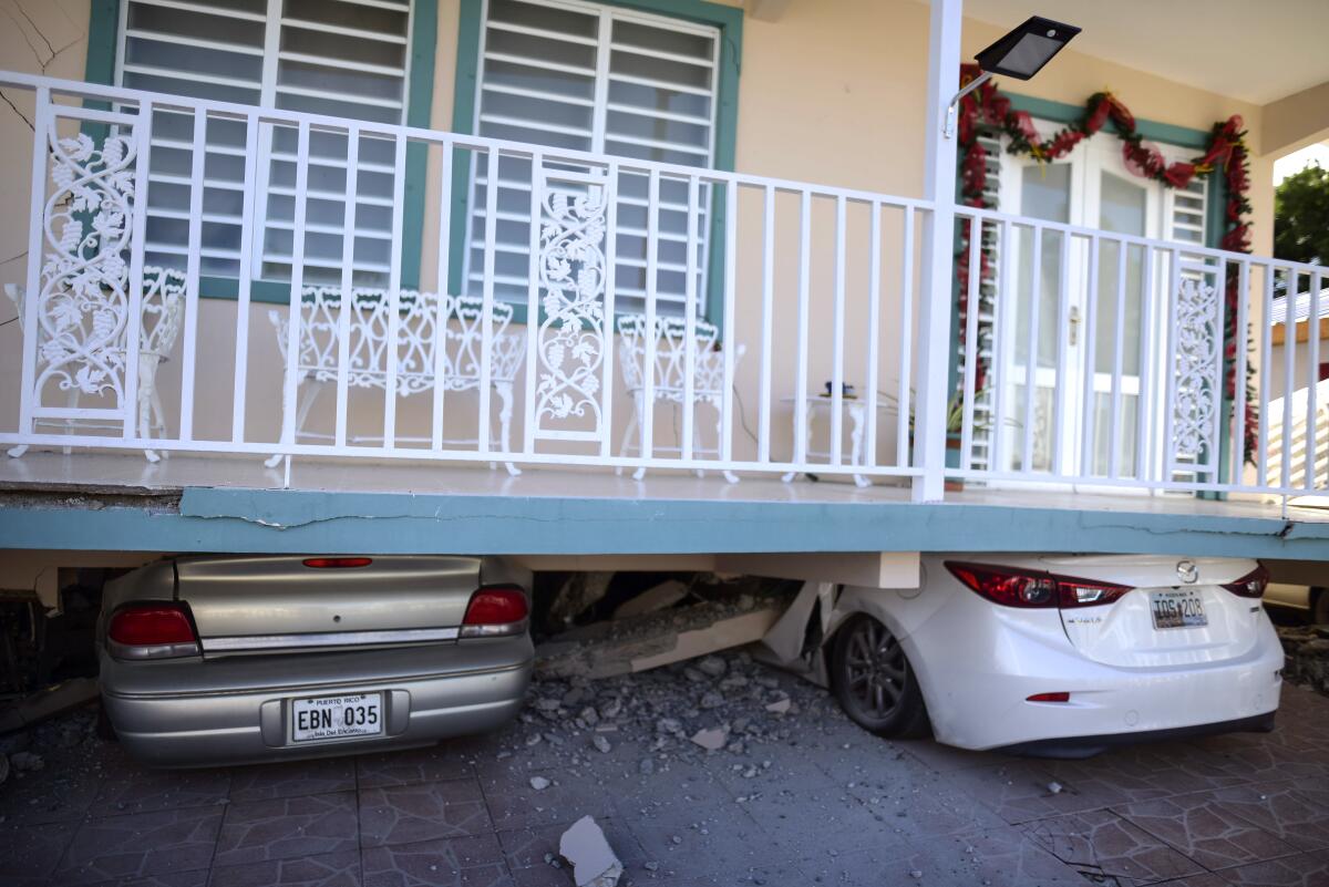 Autos aplastados bajo una casa que se derrumbó después de que un terremoto golpeara Guanica, Puerto Rico, el lunes 6 de enero de 2020. Un terremoto de magnitud 5.8 golpeó a Puerto Rico antes del amanecer del lunes, desatando pequeños deslizamientos de tierra, causando cortes de energía y agrietando gravemente algunas casas. No hubo informes inmediatos de víctimas. (Foto AP/Carlos Giusti)