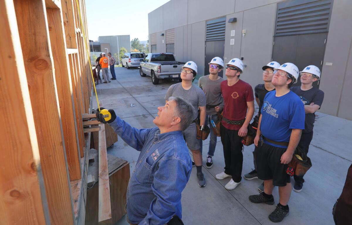 El instructor del proyecto de San Marcos High School Michael McSweeney, muestra a los estudiantes de la preparatoria los errores que necesitan ser corregidos en una de las casas que están construyendo. McSweeney es de la Asociación de la Industria de la Construcción del Condado de San Diego.
