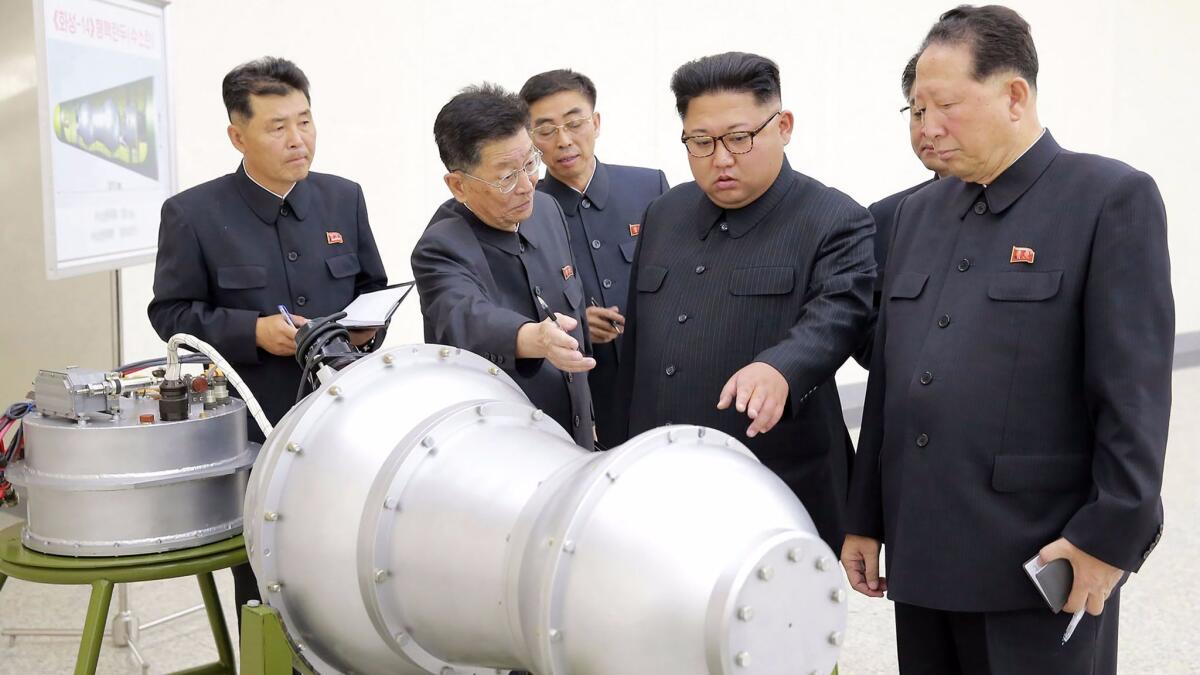 Kim Jong Un, center, examines a device at an undisclosed location in an undated photo released by North Korea's official news agency.