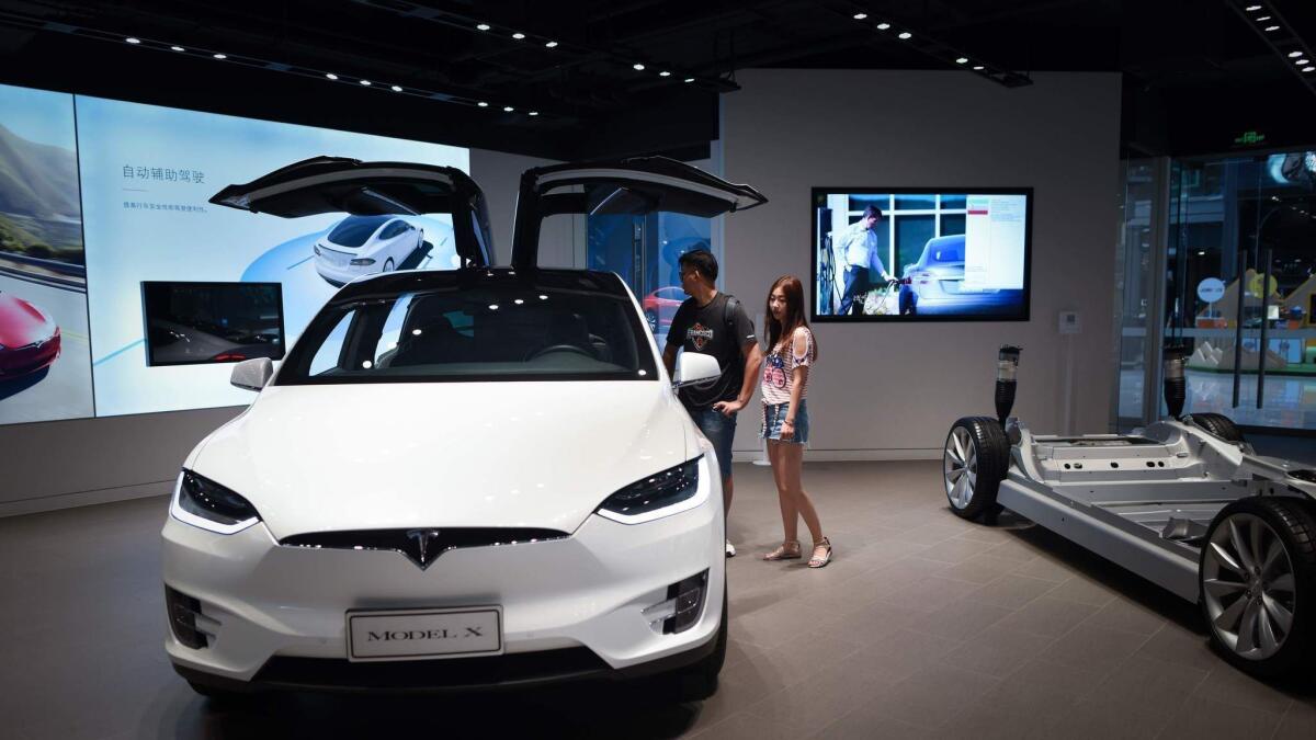 People visit a Tesla showroom in Beijing on July 4,