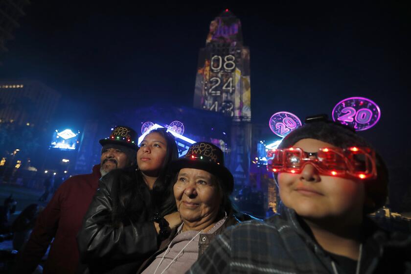 LOS ANGELES, CALIF. - DEC. 31, 2019. The Benitez family listens to the music of Banda Las Angelinas during the New Year's Eve celebration in Grand Park on Tuesday night, Dec. 31, 2019. Family members include, from left: George Benitez, Daniela Benitez, Maria Benitez and Junior Benitez. (Luis Sinco/Los Angeles Times)