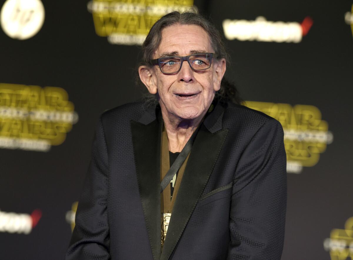 An older man in glasses and a black jacket gazes off camera at an event.