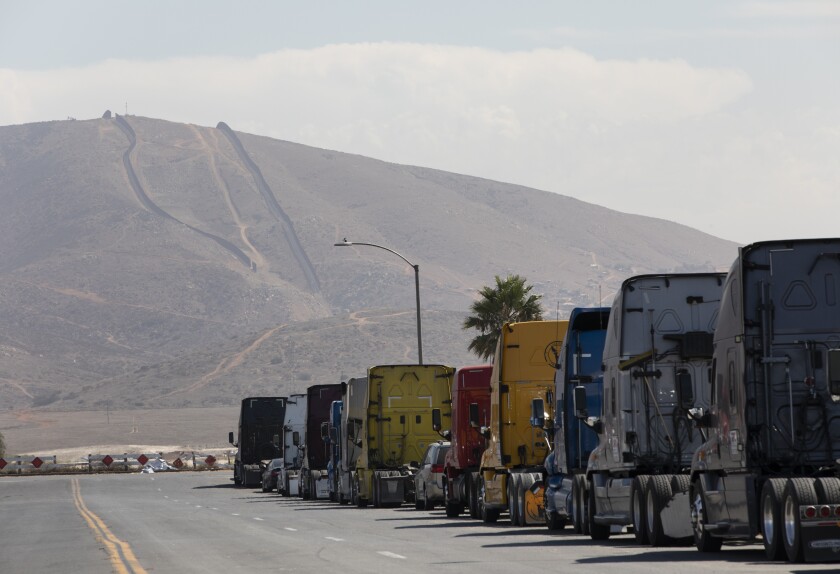 A line of semi-trailer trucks line Enrico Fermi Place, a street minutes away from the Otay Mesa Port of Entry 