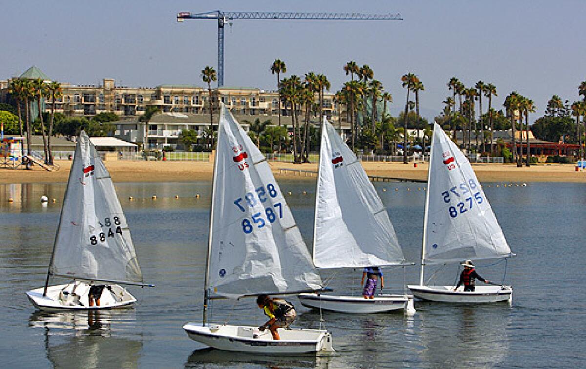 A flotilla of small sailboats float past Mother's Beach and the construction of an apartment complex in Marina del Rey July 14, 2008.