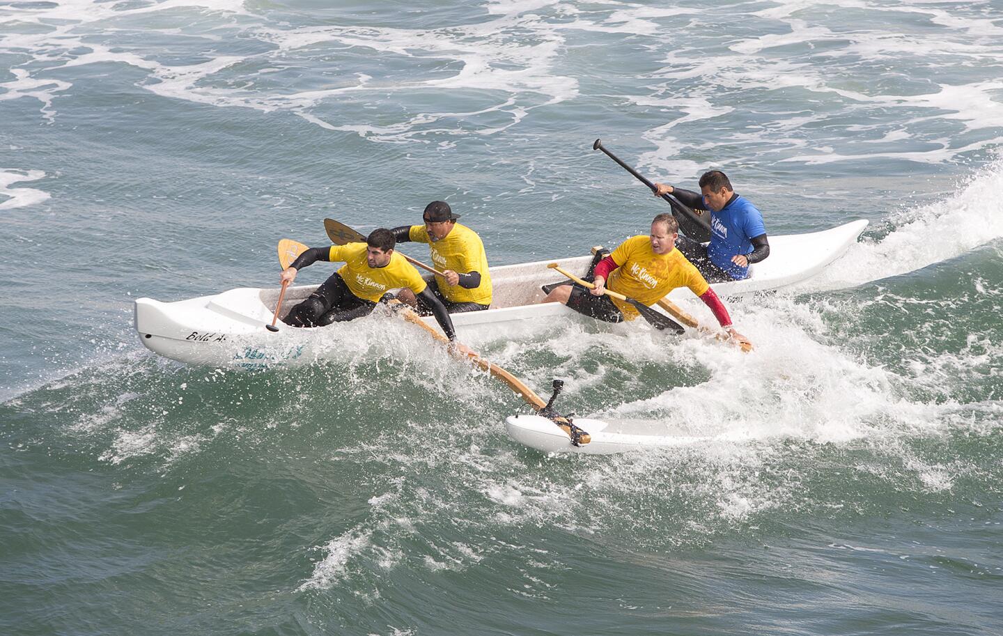 Rocky McKinnon, right, leads his four-man crew over a wave south of the Huntington Beach Pier on Friday, when he debuted an outrigger surfing canoe program called Bold As Love.