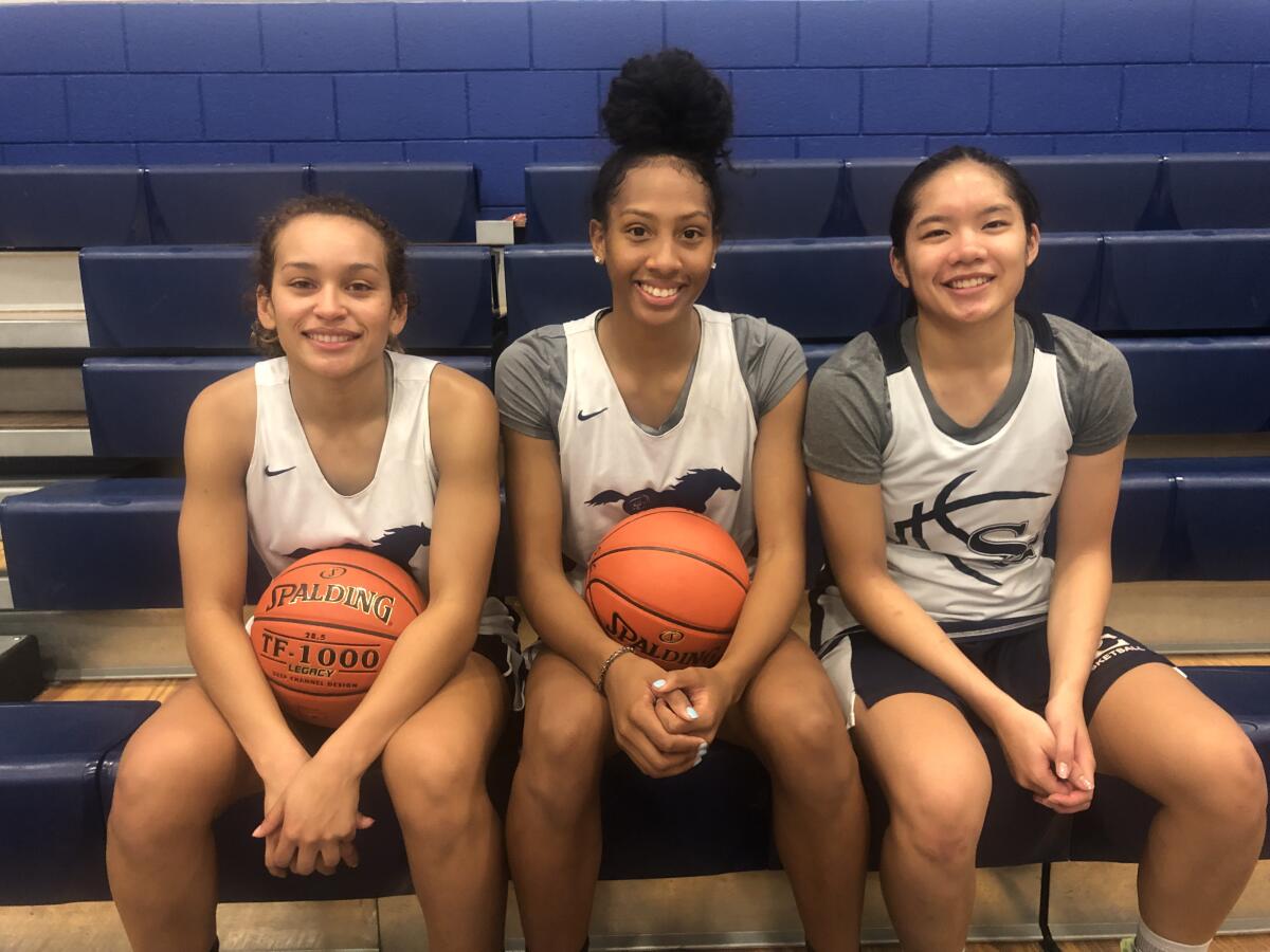 Sierra Canyon’s Ashley Chevalier, left, and Alexis Marks, each holding a basketball, sit with teammate Vanessa De Jesus.
