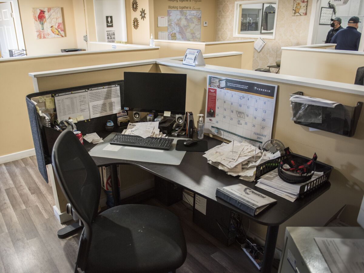 A work station has a laptop, a marked-up calendar, piles of messages and other paperwork. 