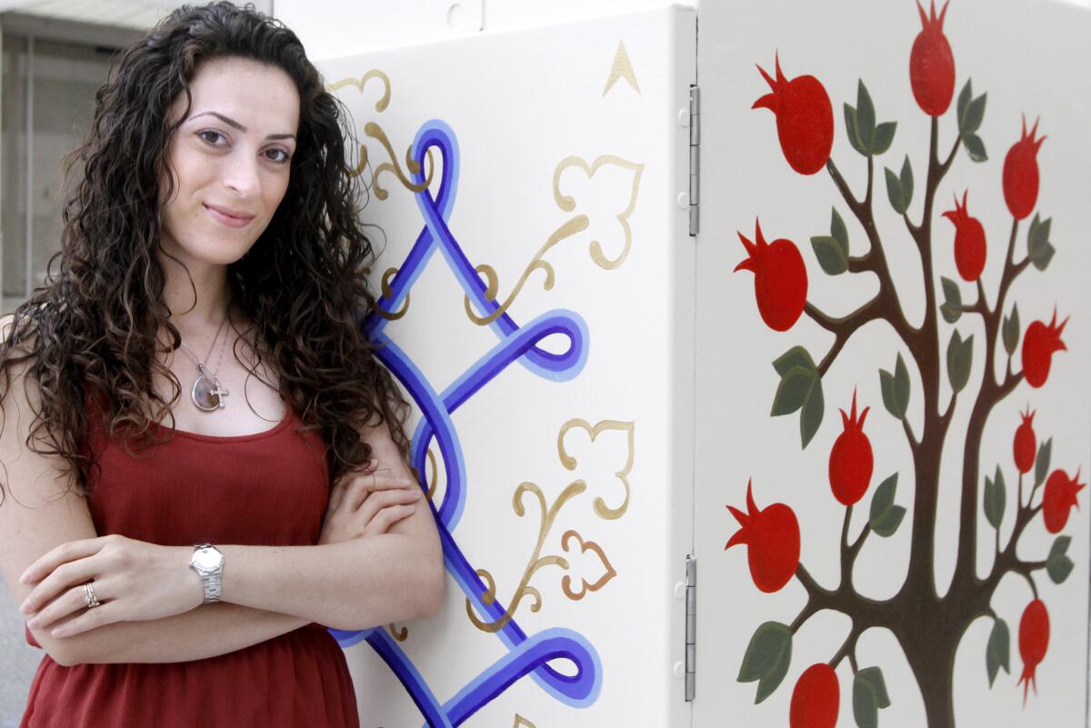 Glendale artist Arpine Shakhbandaryan stands next to the utility box mural she painted at Lexington and Brand Blvd. in Glendale on Wednesday, May 21, 2014. The mural includes a peacock, a pomegranate tree, Glendale spelled out in fancy lettering and artwork representing a map of all 26 murals. The program was sponsored by the Arts & Culture Commission and artists painted 26 utility box murals around Brand Blvd. as part of the Great American Clean Up in Glendale on Saturday, May 17, 2014.