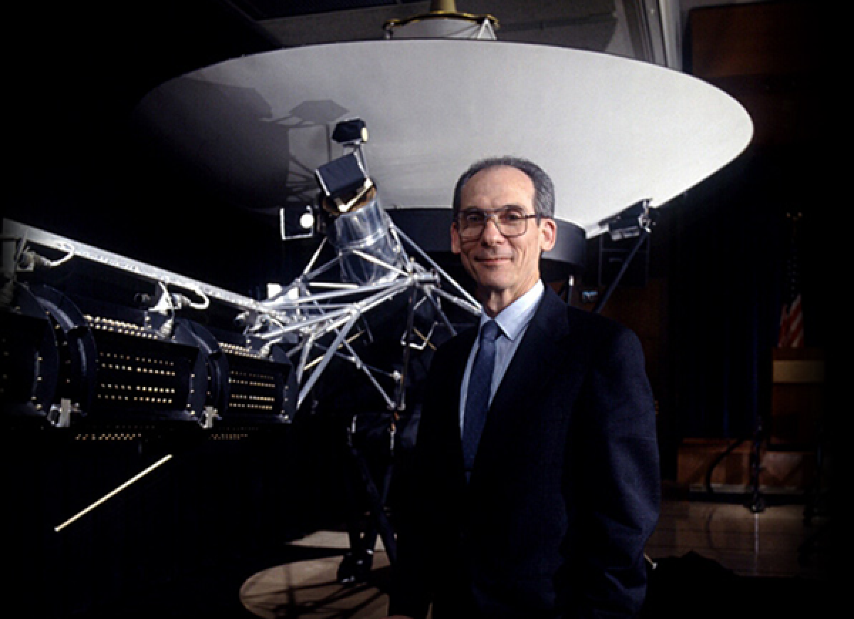 Ed Stone with a model of the Voyager spacecraft behind him.
