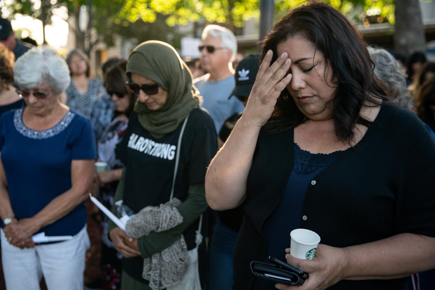 Susan Meyers, Noshaba Afzal and Andrea Nicolette, all of Gilroy, bow their heads during a candlelight vigil at Gilroy City Hall on Monday.