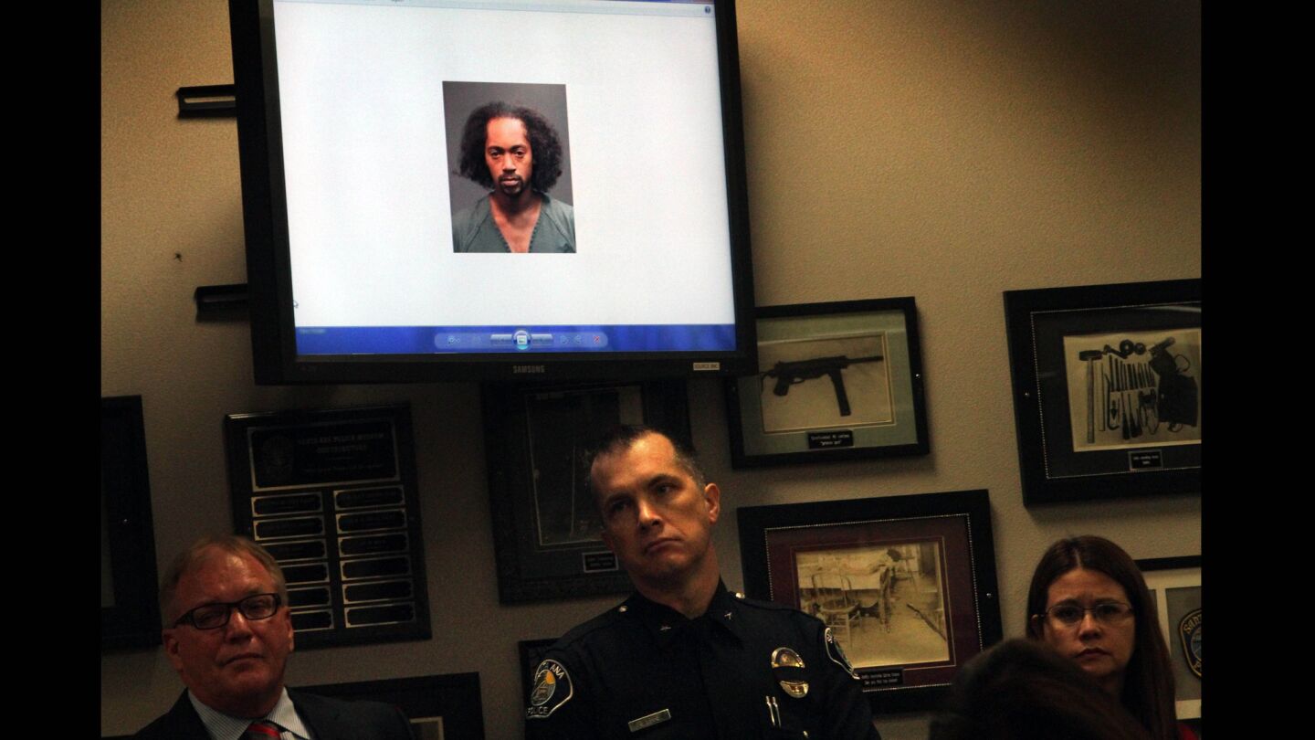 Santa Ana police officers listen to details in the arrest of Jaquinn Bell, pictured above them, in the Halloween night hit-and-run deaths of three teenage girls.
