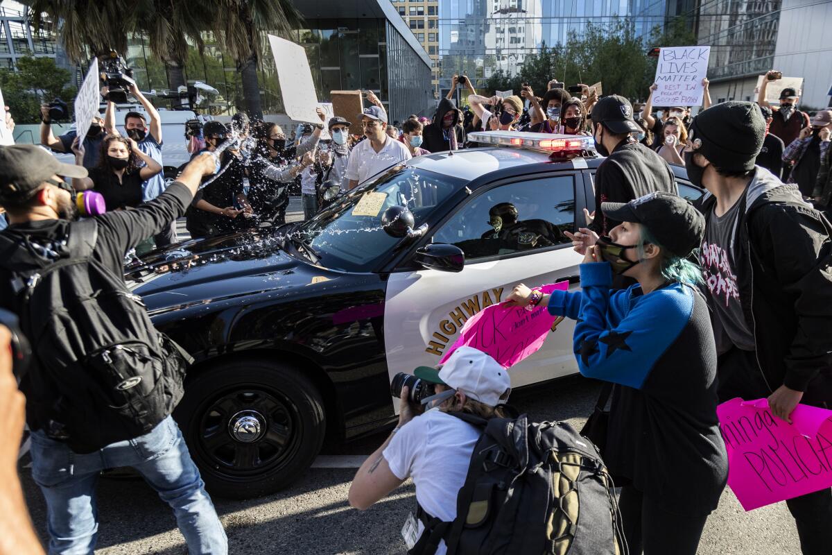  A man throws water on a CHP vehicle during a Black Lives Matter protest in downtown Los Angeles