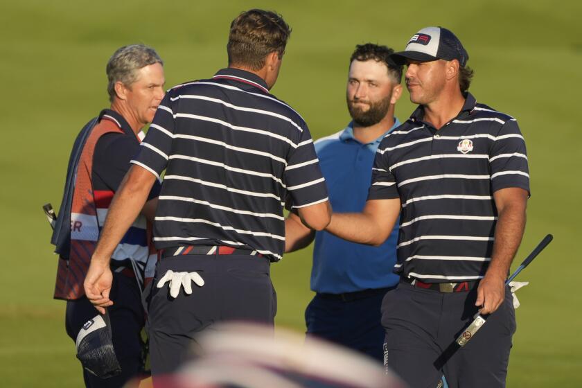 United States' Scottie Scheffler, left shakes hands with United States' Brooks Koepka, right and Europe's Jon Rahm on the 18th green after their match was tied in their afternoon Fourballs match at the Ryder Cup golf tournament at the Marco Simone Golf Club in Guidonia Montecelio, Italy, Friday, Sept. 29, 2023. (AP Photo/Gregorio Borgia )