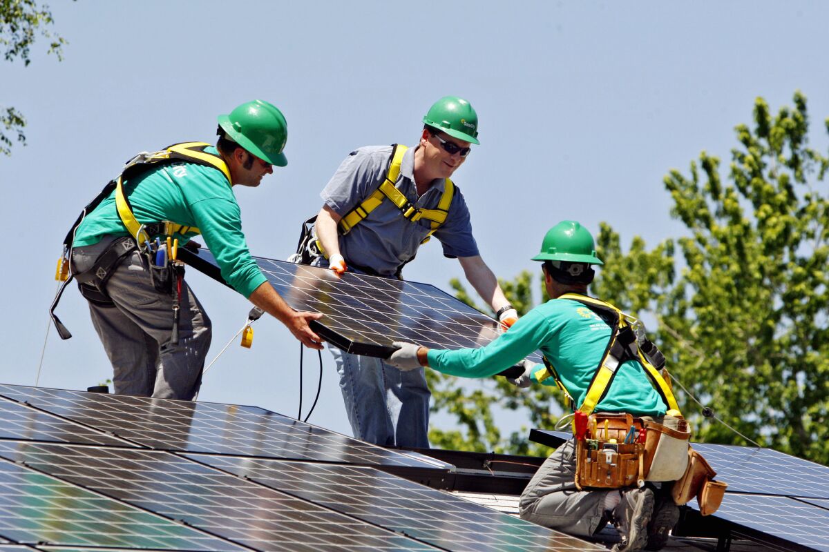 Sen. Michael Bennet (D-Colo.), center, helps SolarCity employees install a solar panel on a home in south Denver in 2010.