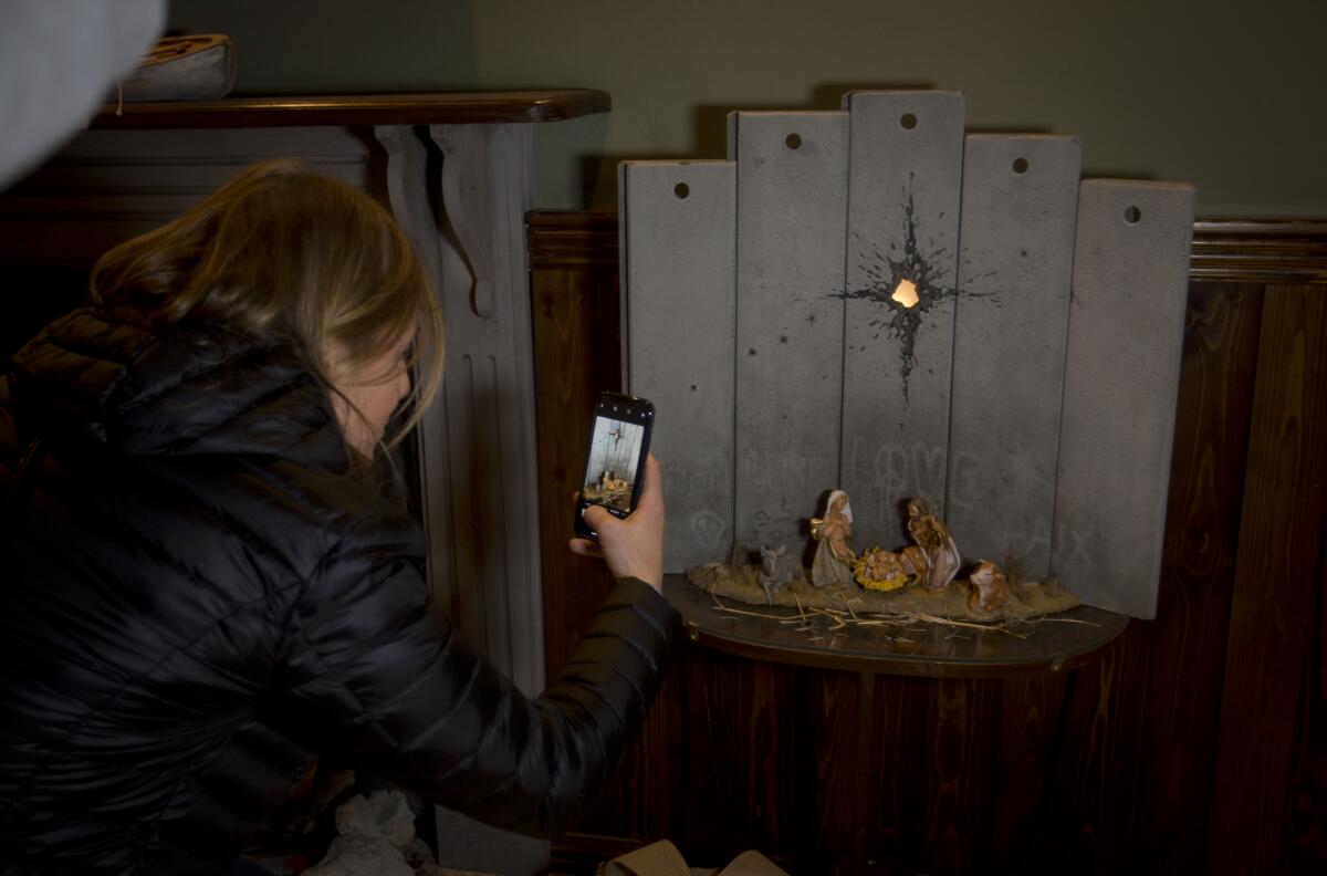 A Christian visitor takes pictures of a new artwork at the Walled Off Hotel.