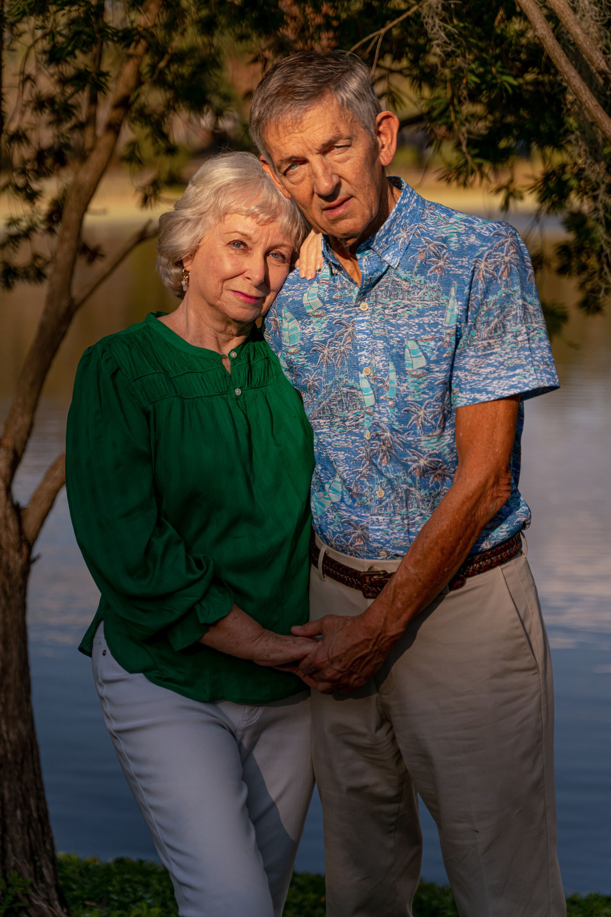 A woman and a man stand side by side holding hands in golden afternoon light.