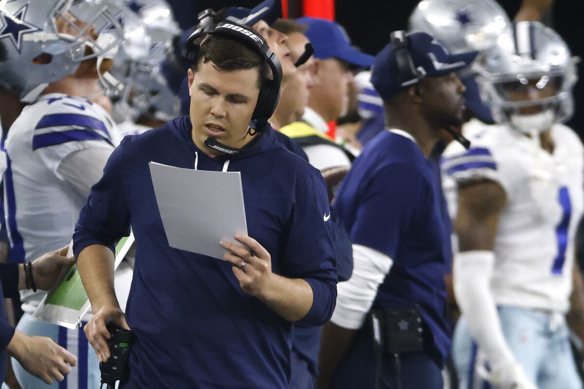 Dallas Cowboys offensive coordinator Kellen Moore calls a play from the sideline.