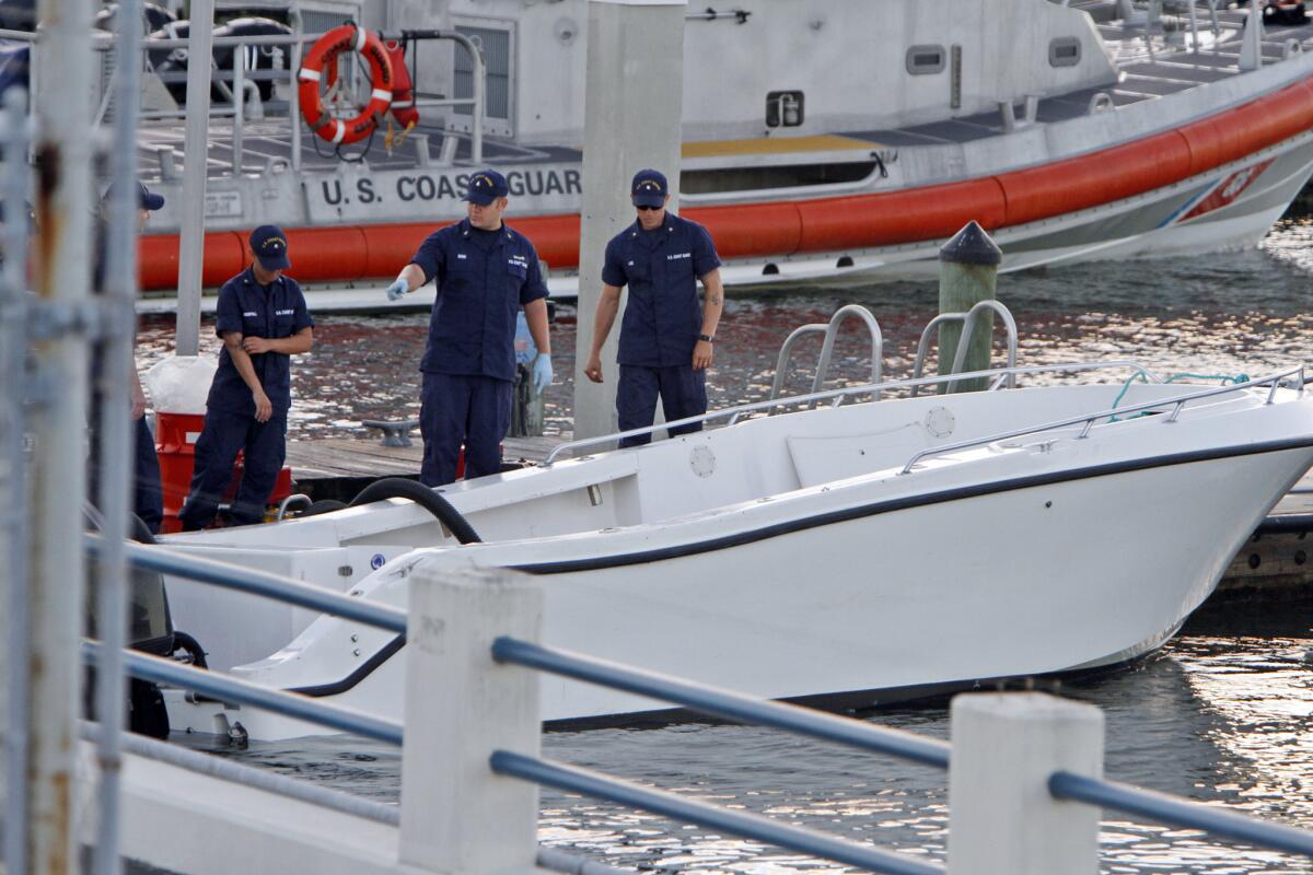 U.S Coast Guard personnel inspect a vessel pulled into shore after it capsized near Miami. At least four women died and 11 people were rescued.