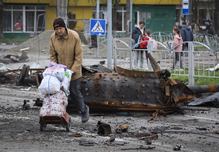 Residente pasa junto a un vehículo militar dañado en Mariupol
