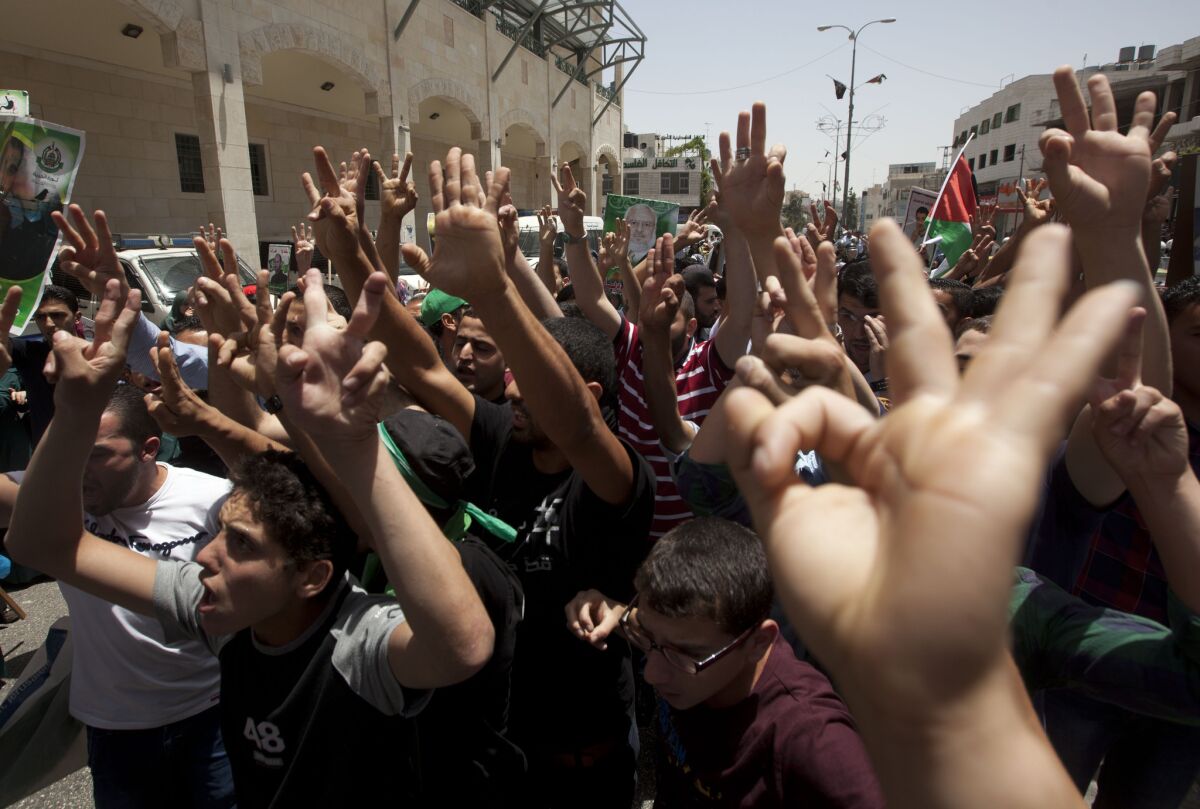 Palestinian backers of Hamas in the West Bank city of Hebron make hand gestures including three raised fingers, a sign of support for the recent abduction of three missing Israeli teens, during a protest against the arrest of 50 Palestinians by Israeli soldiers on Friday.