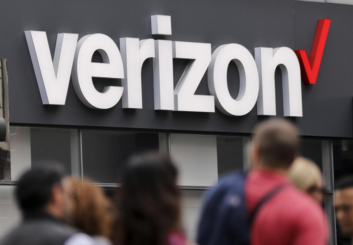 Unas personas caminan frente a un letrero de la empresa Verizon, en Manhattan, el 2 de mayo de 2017. Verizon concretó la compra de Yahoo, un negocio de 4.500 millones de dólares, se informó el 13 de junio de 2017.