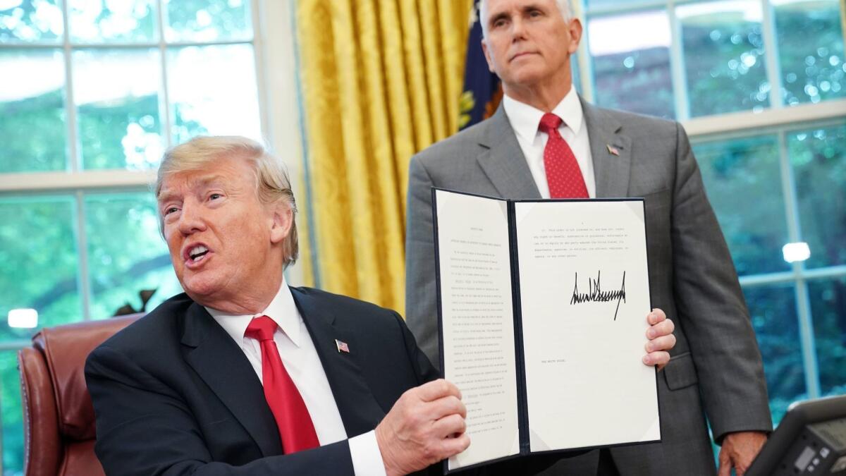 Watched by Vice President Mike Pence, President Trump shows an executive order ending his administration's family separation policy at the border.