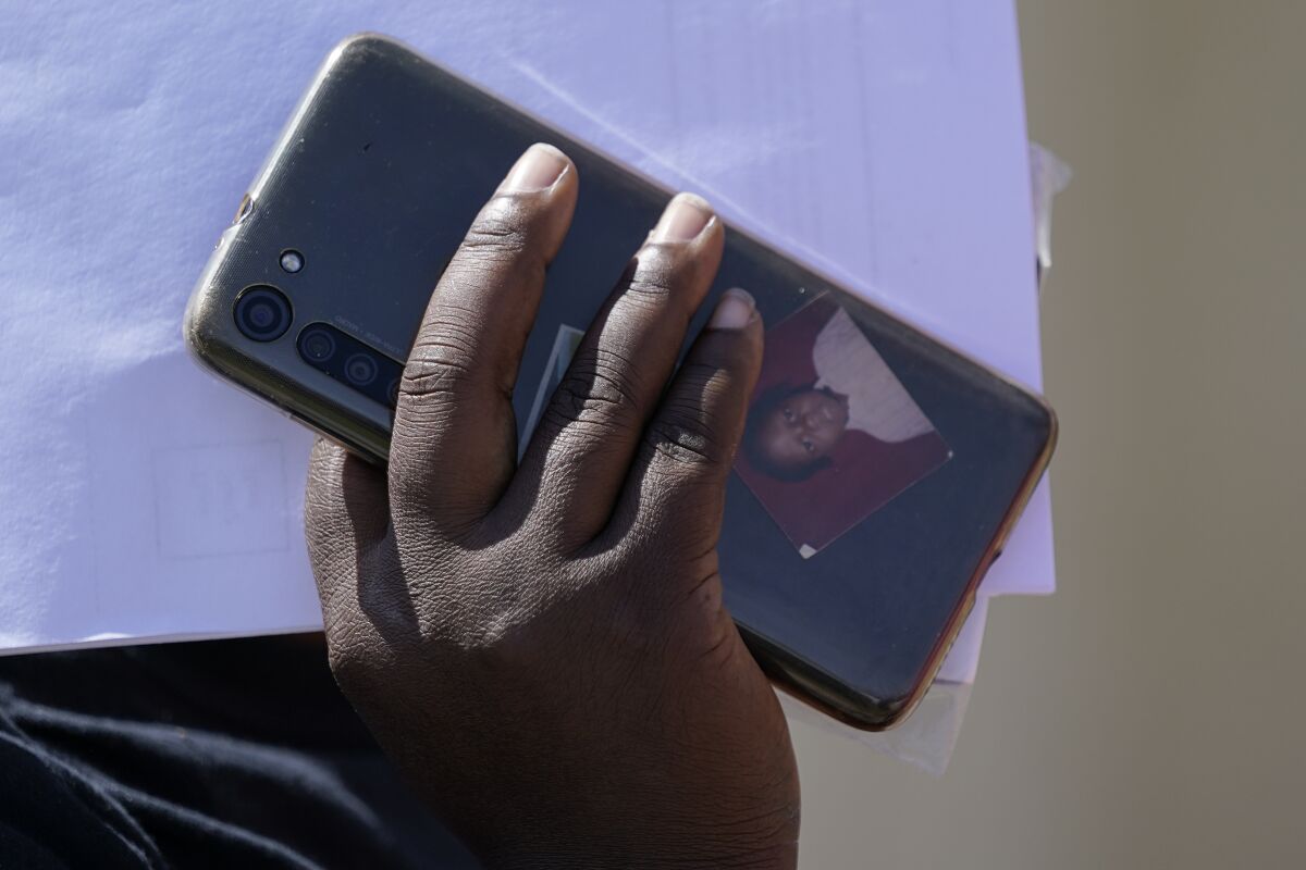 A portrait is seen in a phone case as a migrant arrives at a humanitarian center 