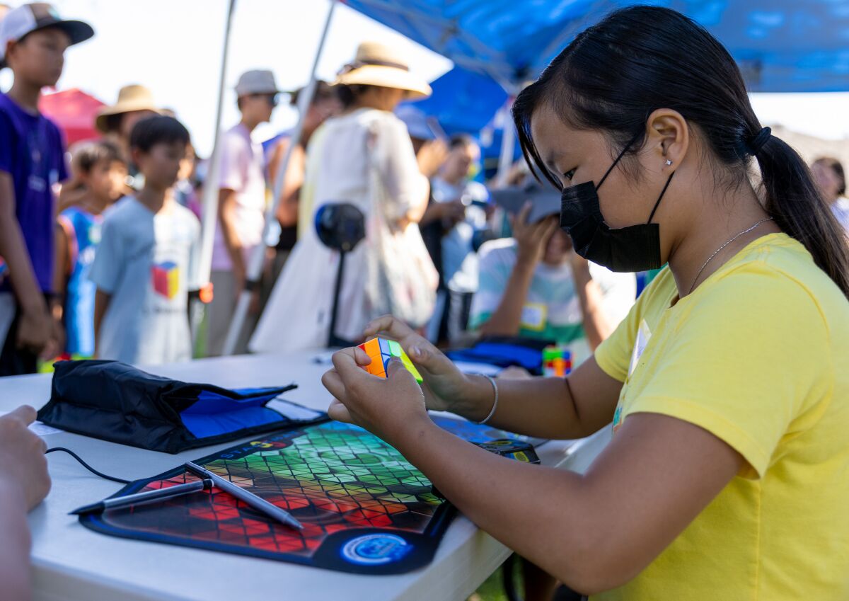 Aileen Vo solves a Rubik's Cube during the "Day of the Cube" Rubik's Cube competition at Los Alamos Park in Fountain Valley.