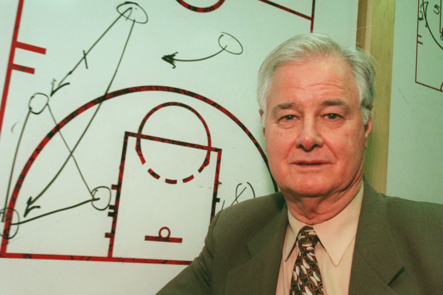 Chicago Bulls' assistant coach Tex Winter stands in front of a diagram of his "triangle" offense in 1997.
