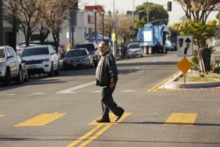 LOS ANGELES, CA - APRIL 17, 2019 - Francisco Blanco cautiously crosses in a new crosswalk with flashing lights has been installed at 85th and Broadway that includes new medians with a space for people to wait to cross the street, if they only make it halfway across before the signal changes as L.A. struggles to reduce fatal traffic crashes on city streets. The city has added new infrastructure -- more visible crosswalks, flashing lights at crosswalks, digital signs that show drivers their speed -- to help protect pedestrians and bicyclists. (Al Seib / Los Angeles Times)